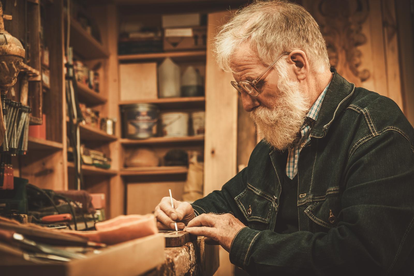 An elderly craftsman practicing a traditional woodworking skill now at risk of disappearing An elderly craftsman practicing a traditional woodworking skill now at risk of disappearing