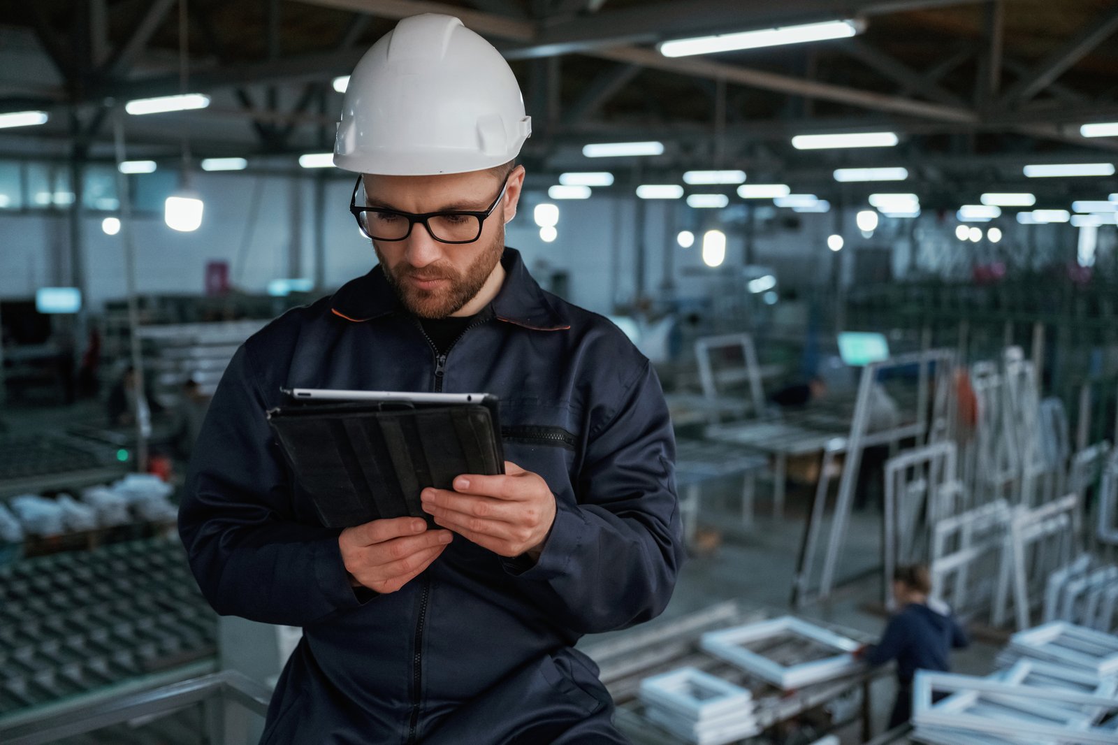 A factory worker reviewing data on a tablet, weighing the hidden costs of automation