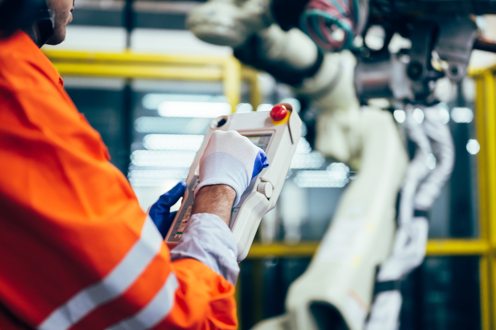 A technician's hand operating a control panel connected to a robotic arm
