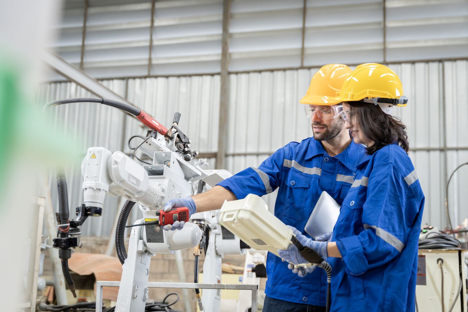 Two technicians working alongside a robot arm, illustrating the shift from Industry 4.0 to 5.0