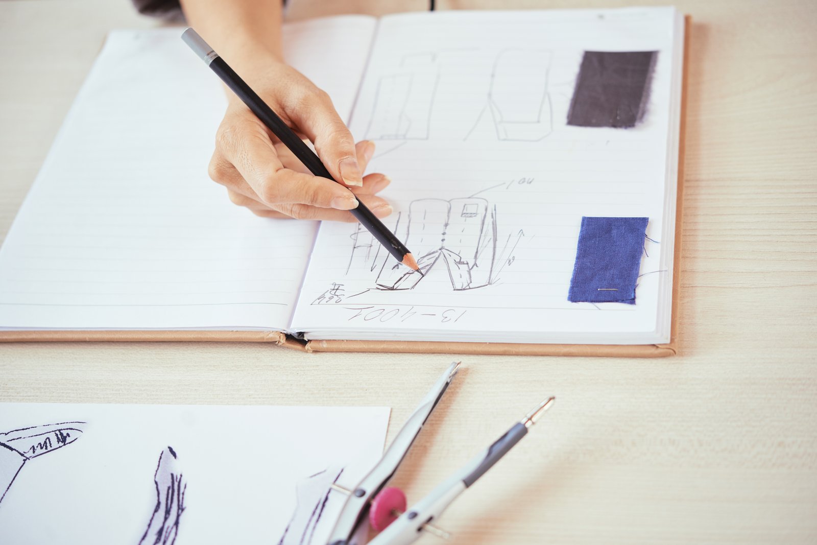 A hand sketching a design concept in a notebook, the first step from sketch to prototype A hand sketching a design concept in a notebook, the first step from sketch to prototype